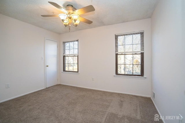 carpeted spare room with baseboards, visible vents, ceiling fan, and a textured ceiling