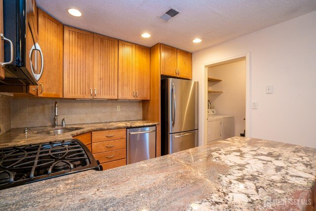 kitchen with visible vents, decorative backsplash, appliances with stainless steel finishes, independent washer and dryer, and a sink