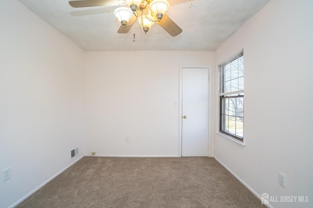 spare room with carpet floors, visible vents, plenty of natural light, and a textured ceiling