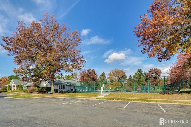 uncovered parking lot with a tennis court and fence