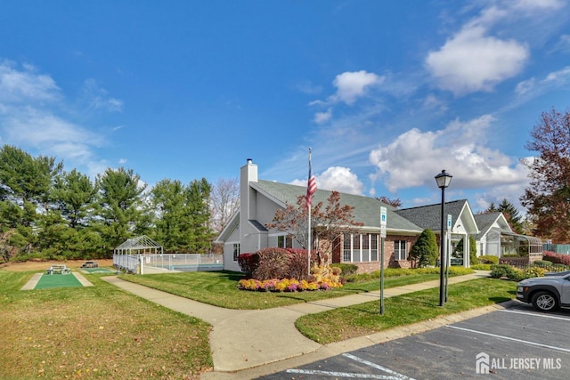 exterior space featuring uncovered parking, brick siding, a lawn, and fence