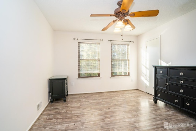 bedroom with a ceiling fan, light wood-type flooring, visible vents, and a textured ceiling