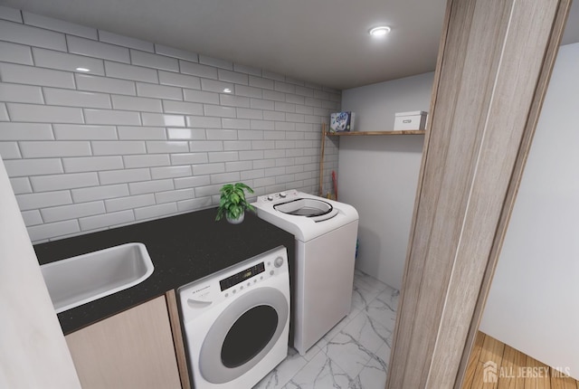 washroom featuring washing machine and clothes dryer, laundry area, marble finish floor, and a sink