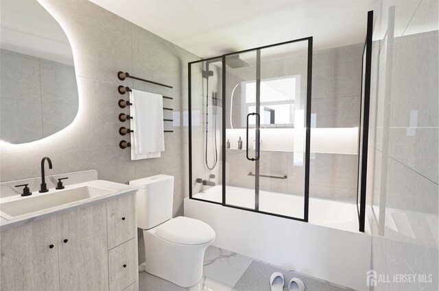 bathroom with toilet, marble finish floor, combined bath / shower with glass door, tile walls, and vanity