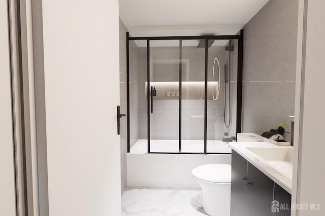 bathroom featuring toilet, marble finish floor, shower / bath combination with glass door, tile walls, and vanity