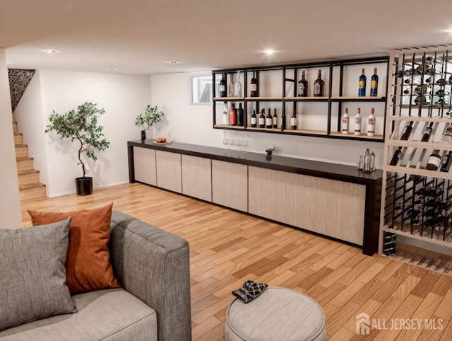 interior space with recessed lighting, a bar, wood finished floors, and stairs