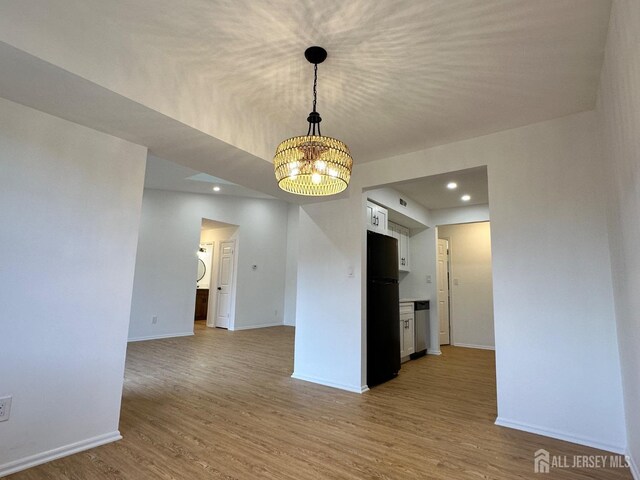 empty room featuring a notable chandelier, recessed lighting, baseboards, and wood finished floors