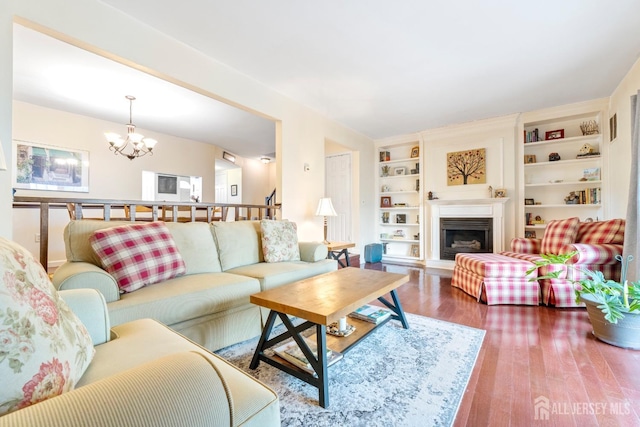 135 Archery Ct, Old Bridge, NJ 08857 - living area with a fireplace with raised hearth, a notable chandelier, built in features, and wood finished floors