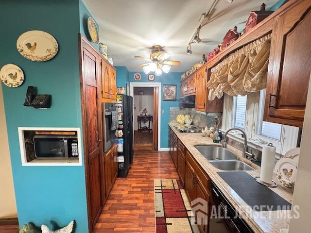 kitchen with stainless steel oven, dark wood finished floors, light countertops, and a sink