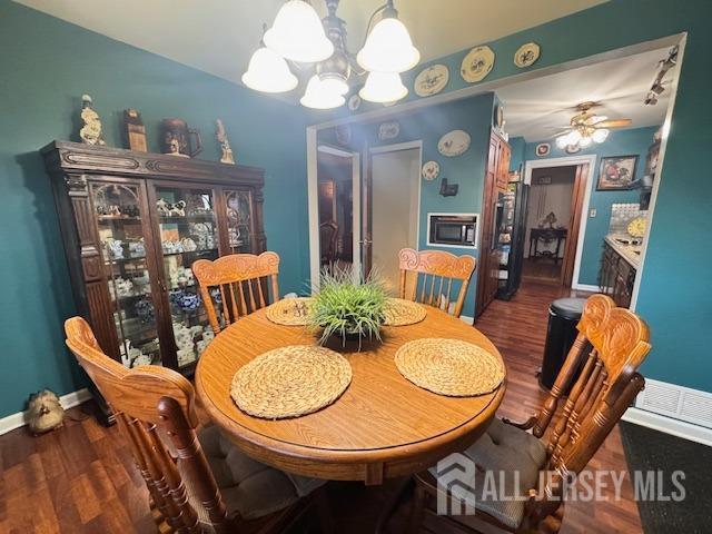 dining room with baseboards, dark wood-type flooring, and a notable chandelier