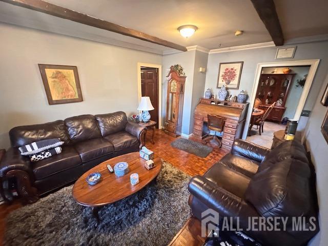 living area with ornamental molding and beam ceiling