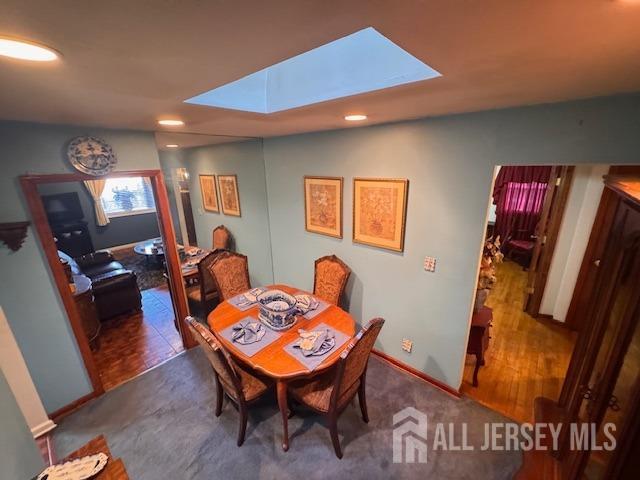 dining room featuring a skylight and baseboards