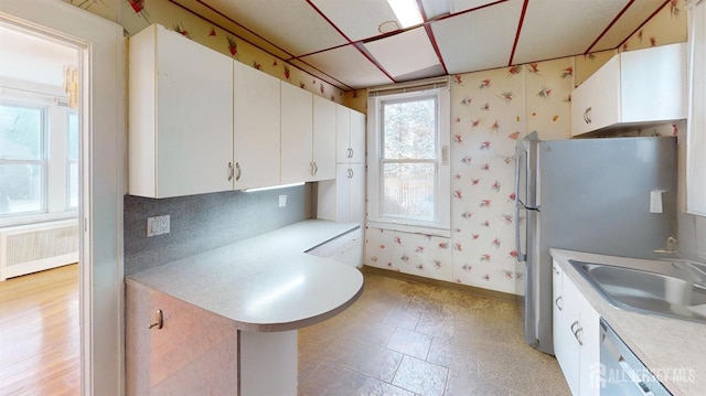 kitchen with white cabinetry, radiator heating unit, stainless steel appliances, and sink