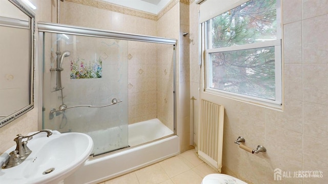 bathroom with radiator, plenty of natural light, sink, and combined bath / shower with glass door