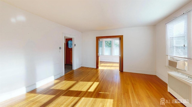 empty room with radiator, hardwood / wood-style floors, and cooling unit