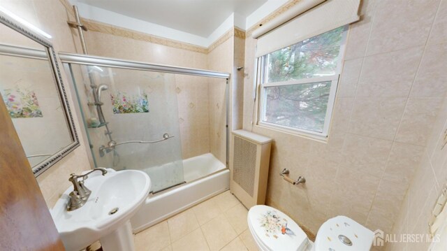 full bathroom with combined bath / shower with glass door, sink, radiator heating unit, and toilet