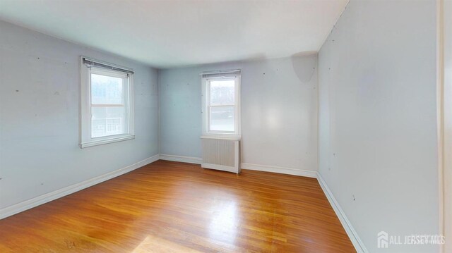 spare room featuring radiator heating unit and light hardwood / wood-style flooring