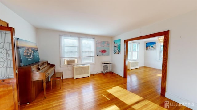 miscellaneous room featuring cooling unit, radiator, and light hardwood / wood-style flooring