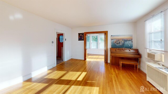 misc room featuring cooling unit, hardwood / wood-style floors, and radiator heating unit