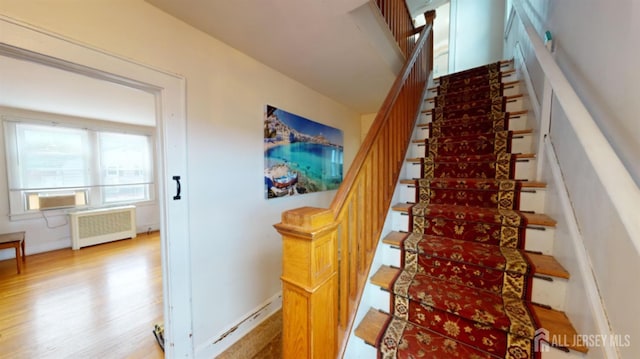 staircase featuring radiator and hardwood / wood-style floors