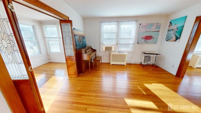 miscellaneous room with radiator heating unit, light hardwood / wood-style floors, and cooling unit