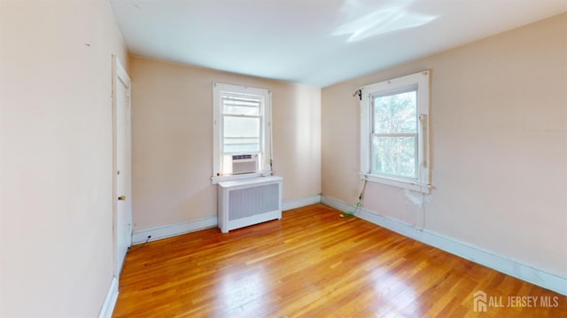 unfurnished bedroom featuring radiator, cooling unit, and light hardwood / wood-style floors