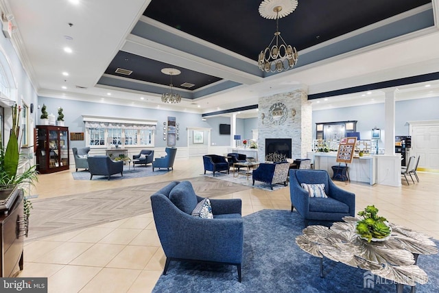 living room featuring a raised ceiling, light tile patterned flooring, ornamental molding, and decorative columns