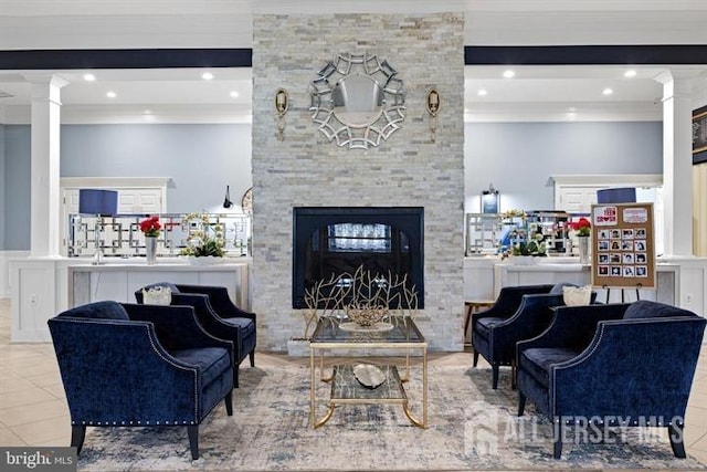 living room with tile patterned flooring, a stone fireplace, and ornate columns