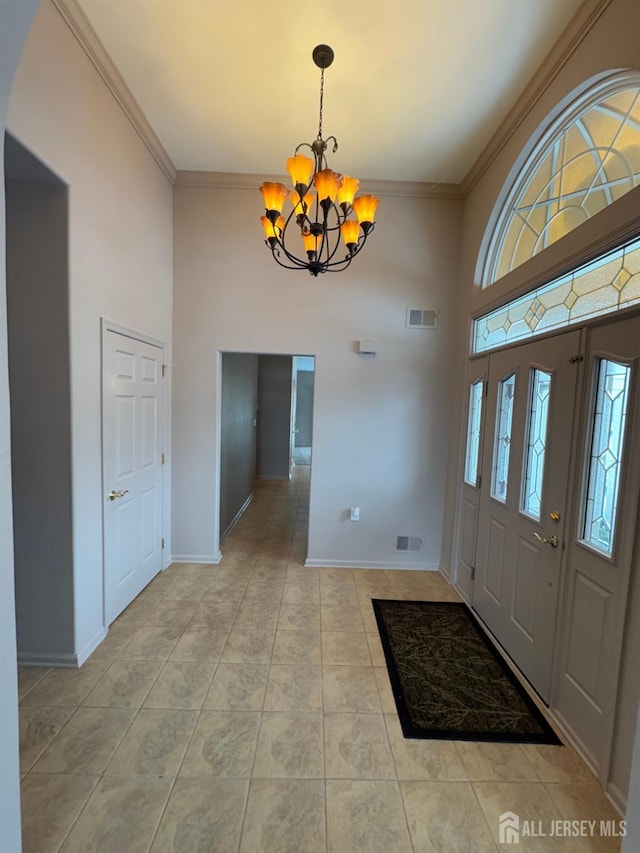 tiled entryway with crown molding, a wealth of natural light, and a chandelier