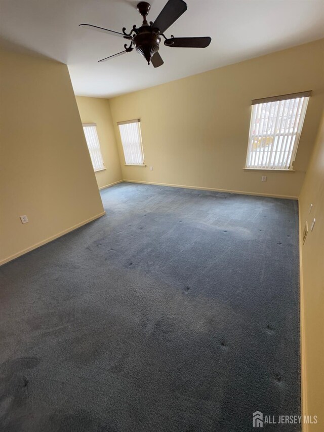 carpeted empty room with baseboards and a ceiling fan