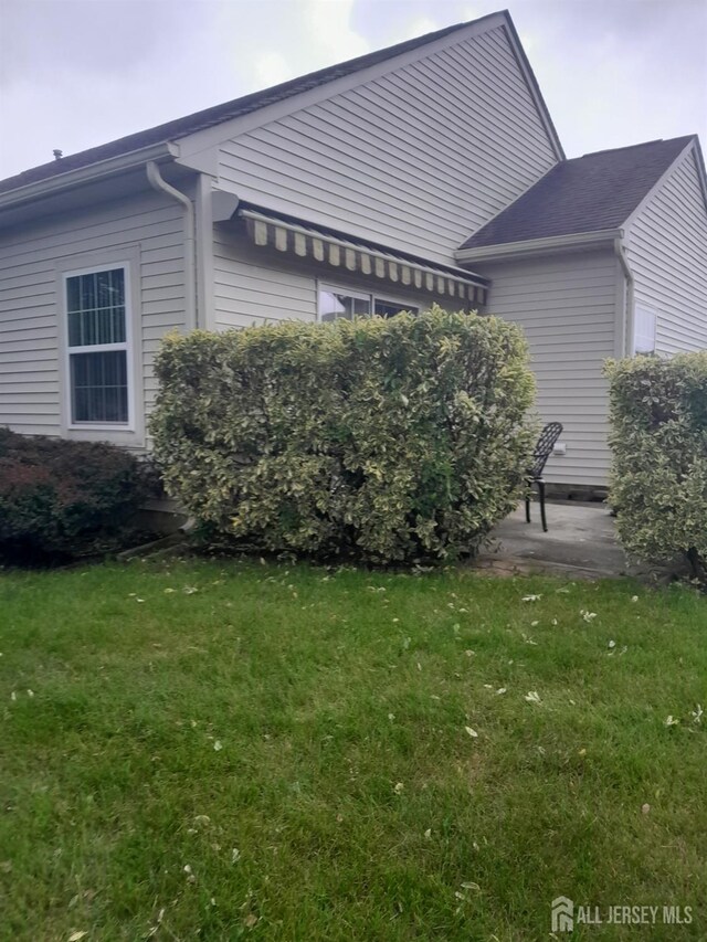 view of side of property featuring a lawn and a patio