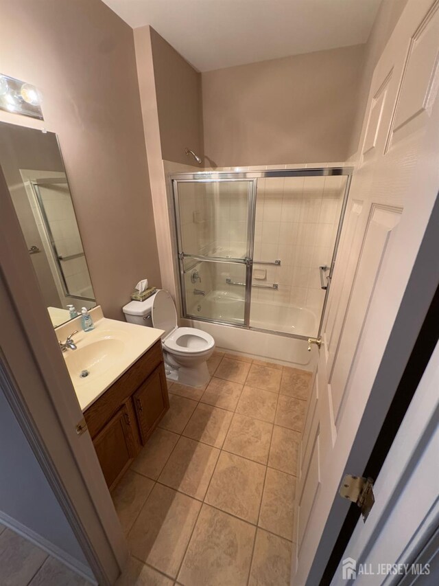 bathroom featuring bath / shower combo with glass door, vanity, toilet, and tile patterned floors