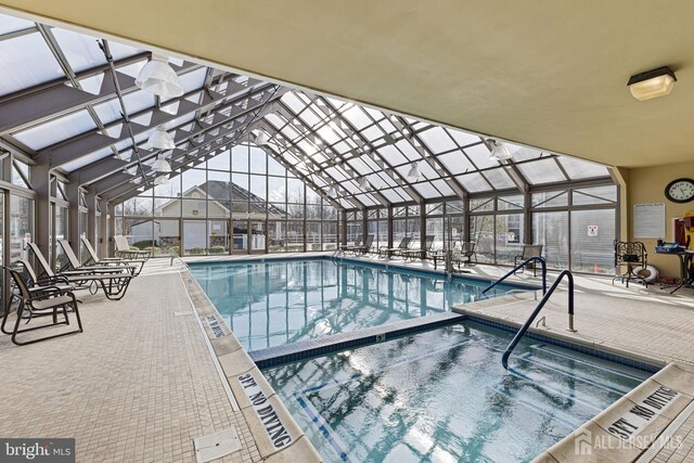 community pool with an indoor in ground hot tub, a patio area, and a lanai