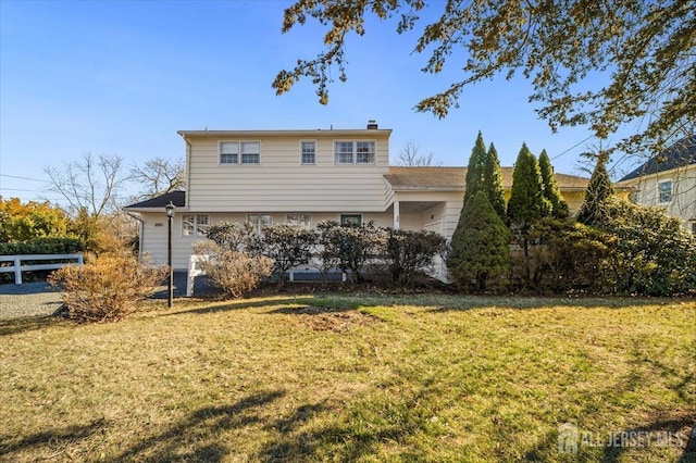 back of property featuring a lawn, a chimney, and fence