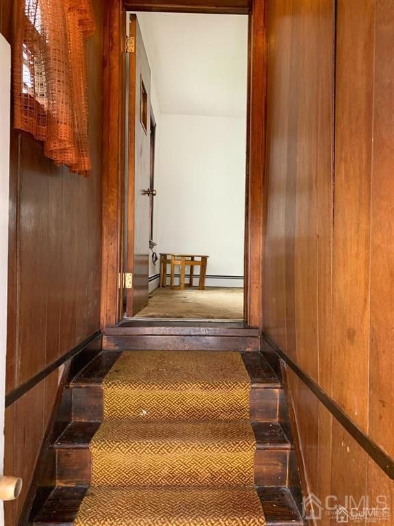 stairs with wooden walls and a baseboard radiator