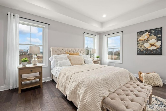 bedroom featuring dark wood-type flooring, a tray ceiling, baseboards, and recessed lighting