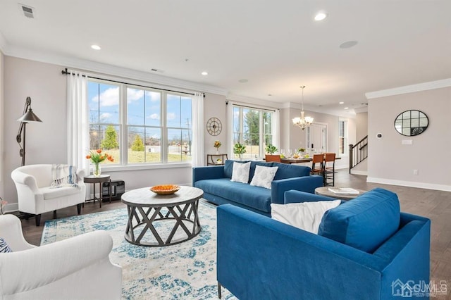 living room with baseboards, ornamental molding, a chandelier, visible vents, and wood finished floors