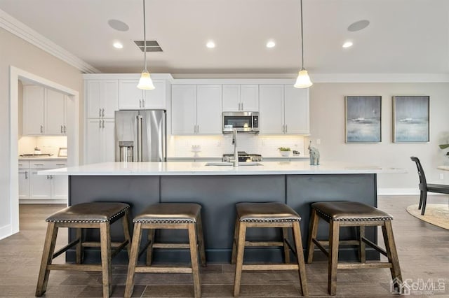 kitchen with white cabinets, visible vents, appliances with stainless steel finishes, and ornamental molding