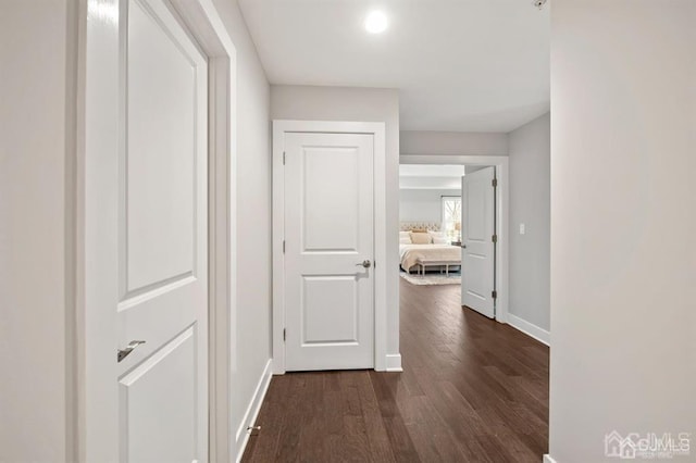 hall featuring dark wood-type flooring and baseboards