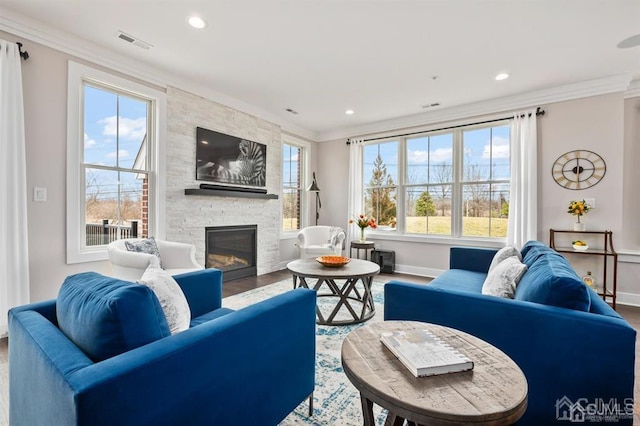 living area with crown molding, a stone fireplace, recessed lighting, wood finished floors, and baseboards