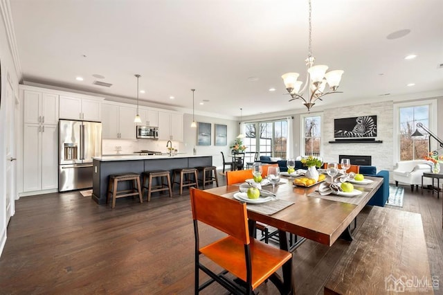 dining area featuring a wealth of natural light, a stone fireplace, dark wood finished floors, and recessed lighting