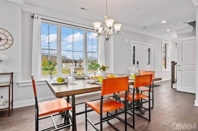 dining room with ornamental molding, visible vents, wood-type flooring, and an inviting chandelier