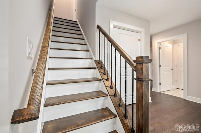 staircase featuring baseboards and wood finished floors