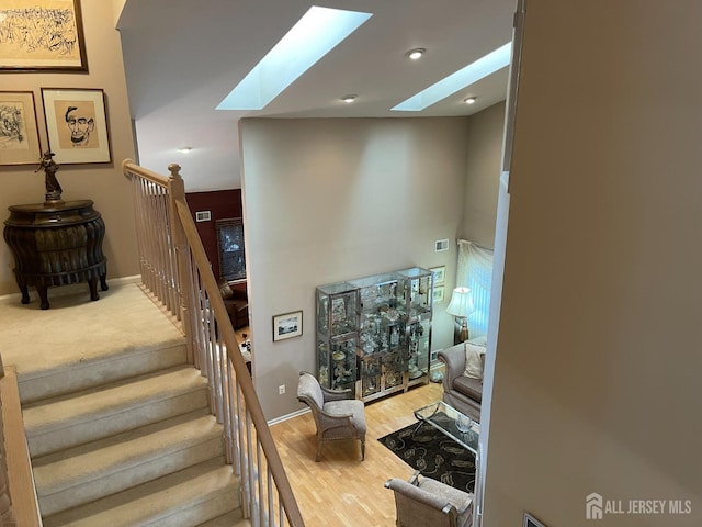 staircase with wood-type flooring and a skylight