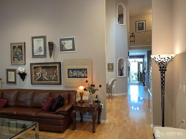 living room with a towering ceiling and light wood-type flooring