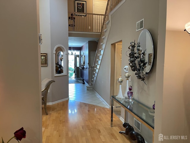 hall featuring a high ceiling, an inviting chandelier, and light wood-type flooring