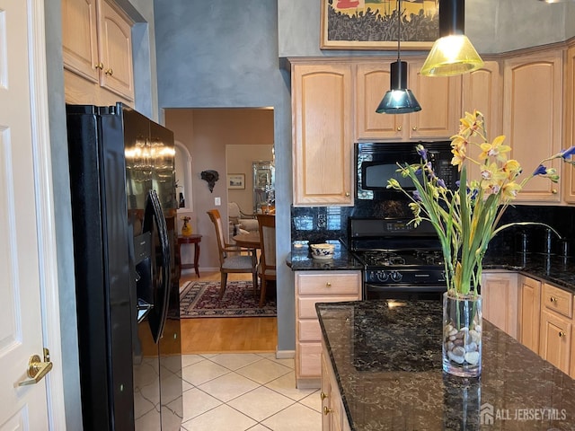 kitchen with decorative light fixtures, dark stone countertops, light brown cabinets, and black appliances