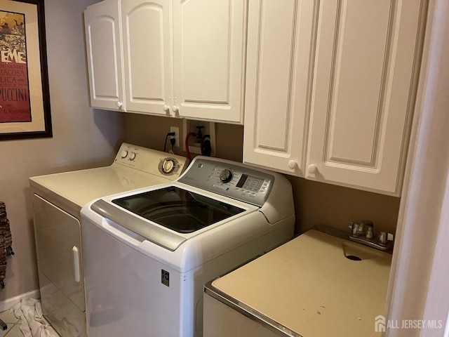 laundry area featuring separate washer and dryer, sink, and cabinets