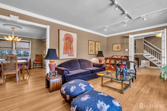 living room with crown molding, wood-type flooring, and an inviting chandelier