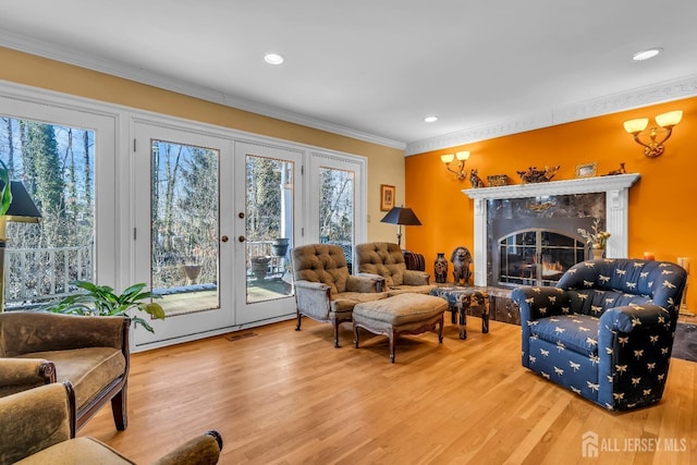 living room with hardwood / wood-style flooring, ornamental molding, a fireplace, and french doors